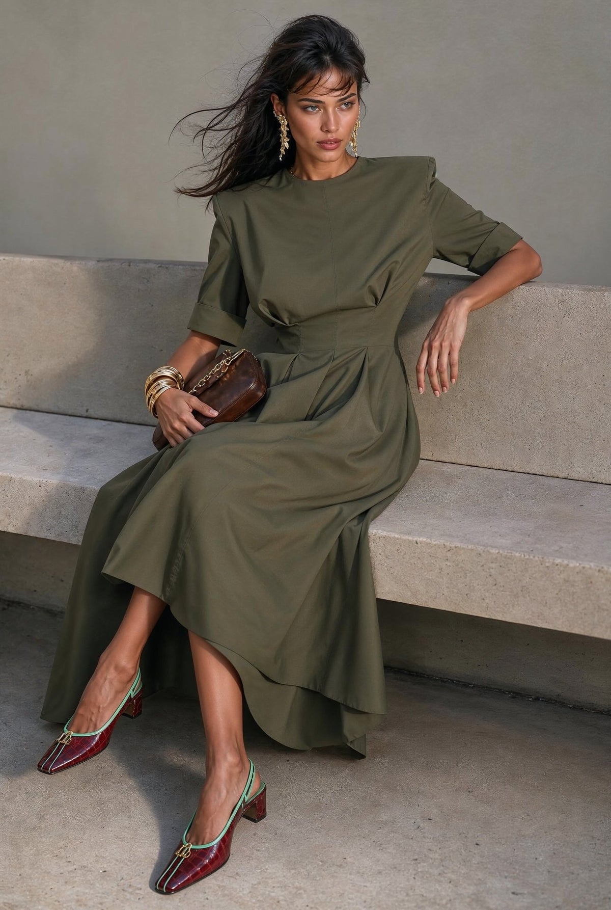 Audrey army-green dress with structured shoulders and pleated skirt, seated view