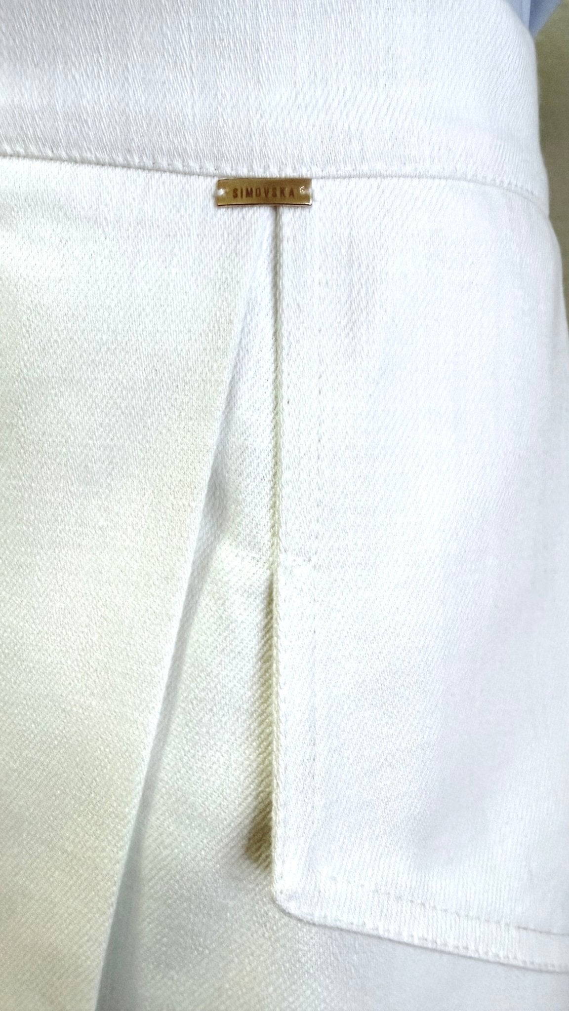 Close-up of Margot skirt’s white denim wrap panel and concealed front slit