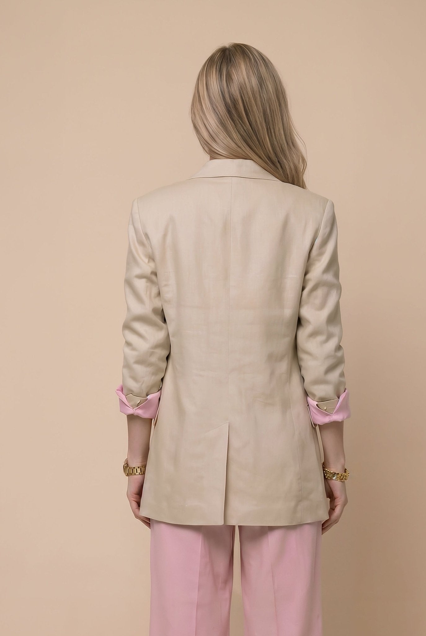 Woman wearing a beige blazer and pink pants against a beige background